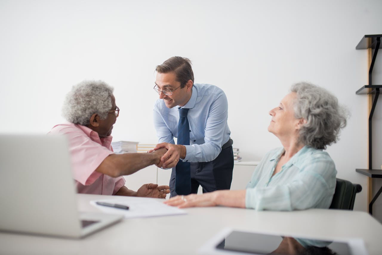 Business professional meeting with senior clients in an office setting, showcasing diversity and cooperation.
